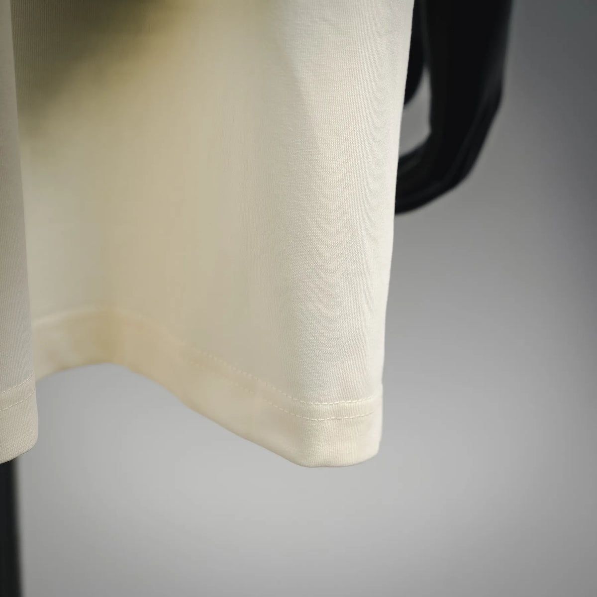 Cream short-sleeve T-shirt, close-up of hem stitching and curved bottom