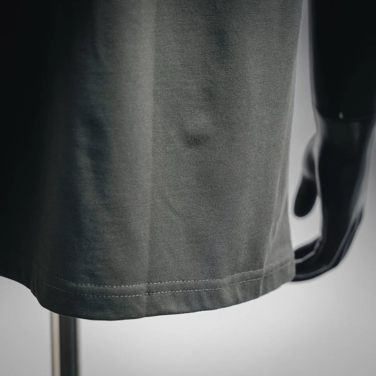Dark gray T-shirt hem detail with stitched bottom and draped fabric texture