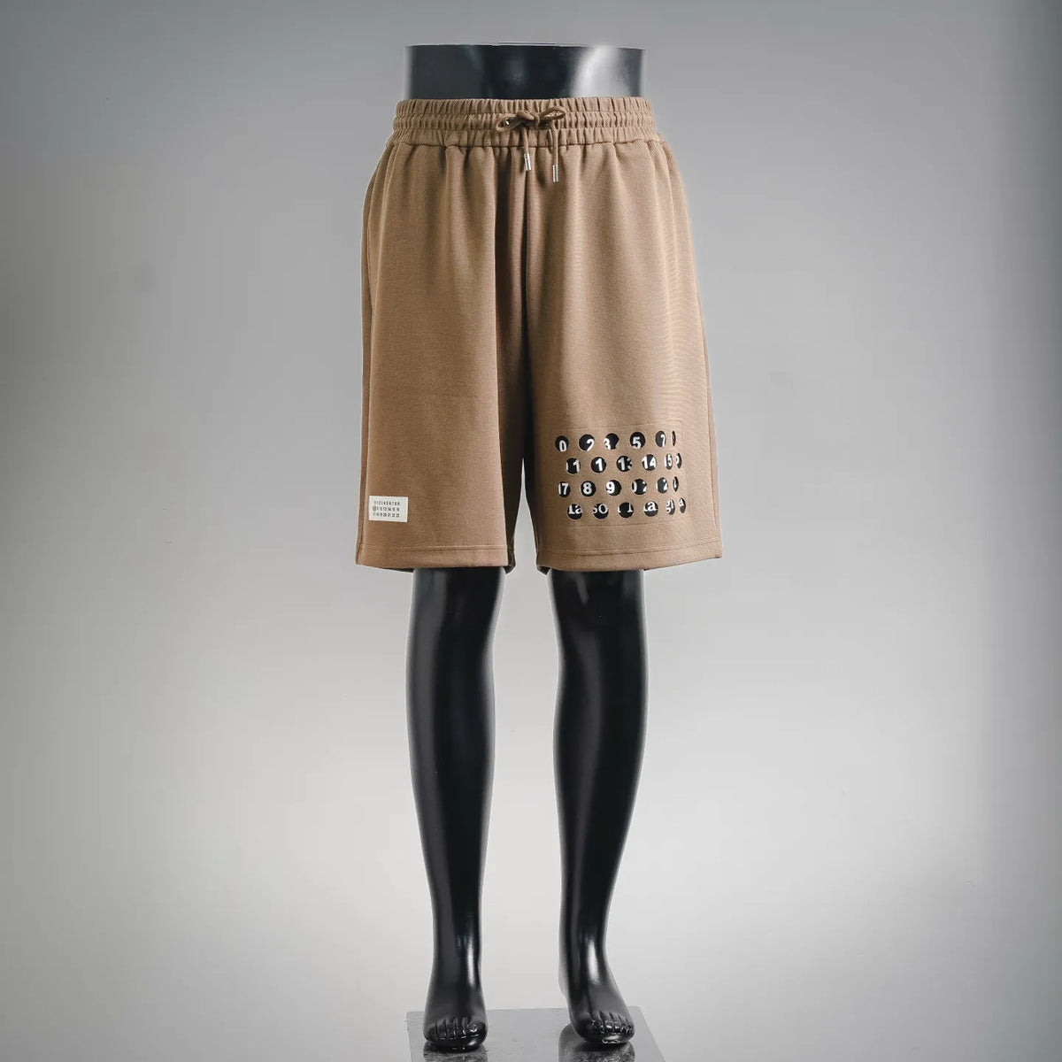 Tan elastic-waist shorts with front logo print, side pocket, and straight hem