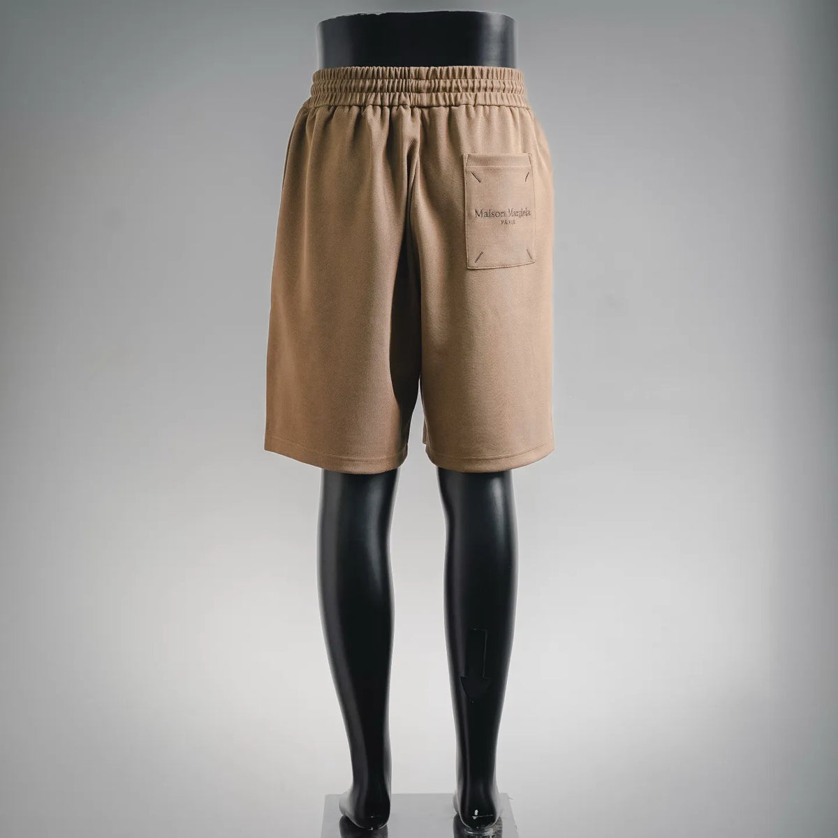 Tan elastic-waist shorts with back welt pocket and Maison Margiela Paris logo