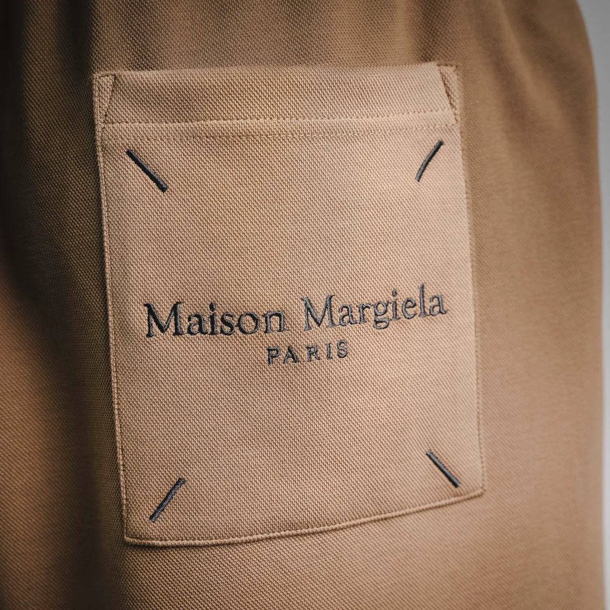 Tan fabric pocket label with Maison Margiela PARIS text and dark stitch corners