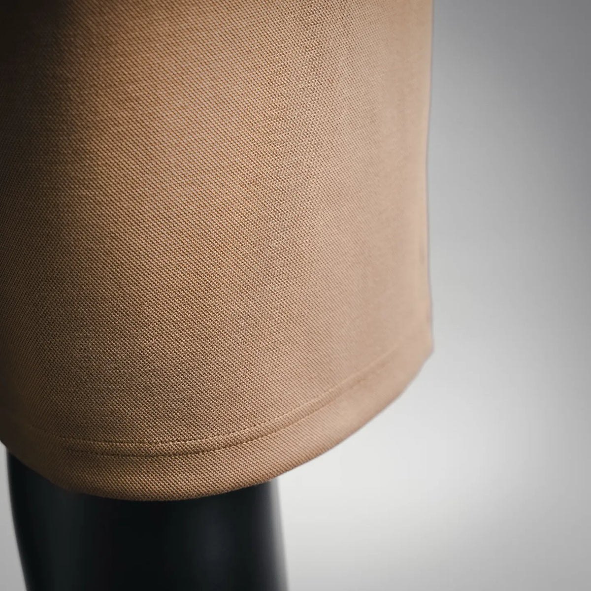 Tan shorts leg hem with curved stitch line at the bottom edge