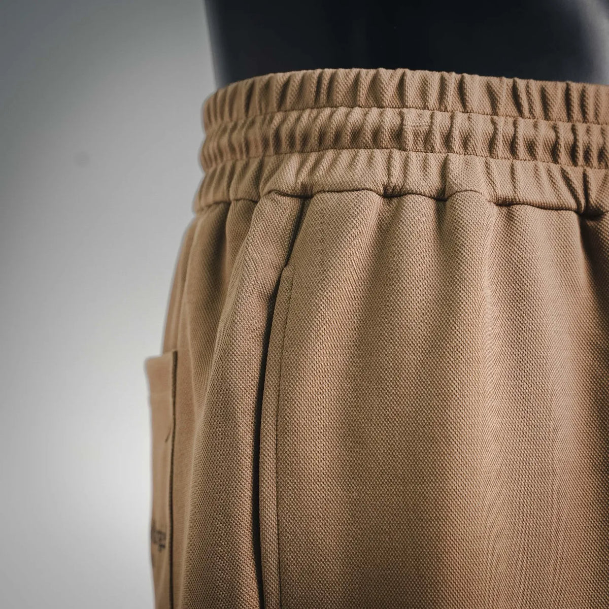 Tan shorts waistband with elastic casing and drawstring tie at the side