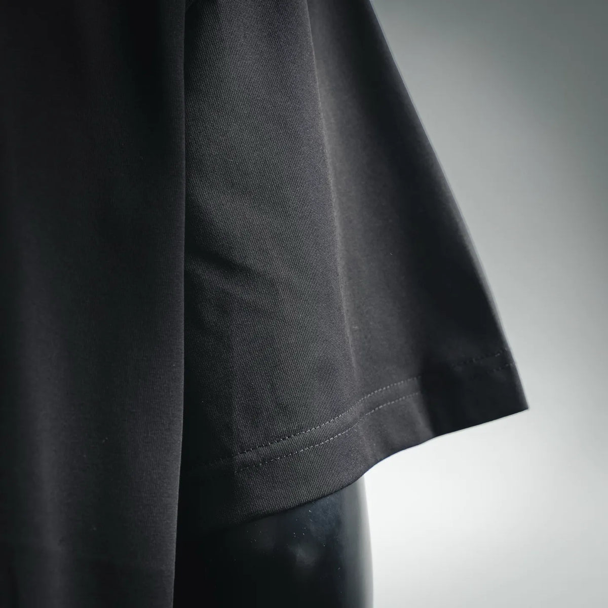 Black short-sleeve T-shirt sleeve close-up with seam stitching.