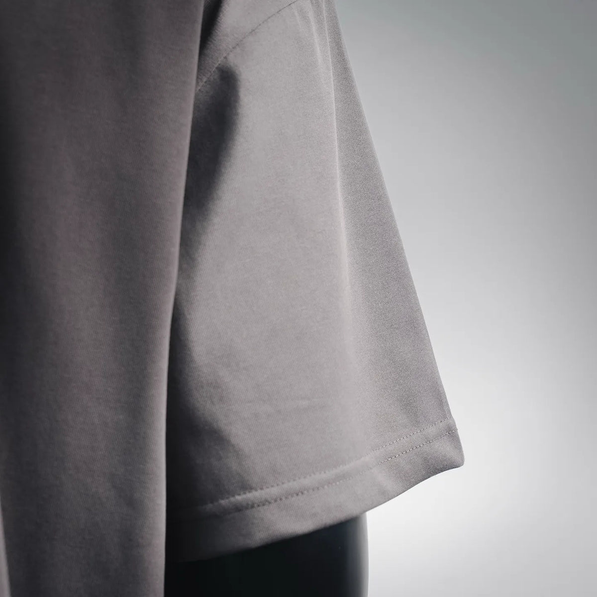 Gray T-shirt sleeve and side seam detail with neat stitching