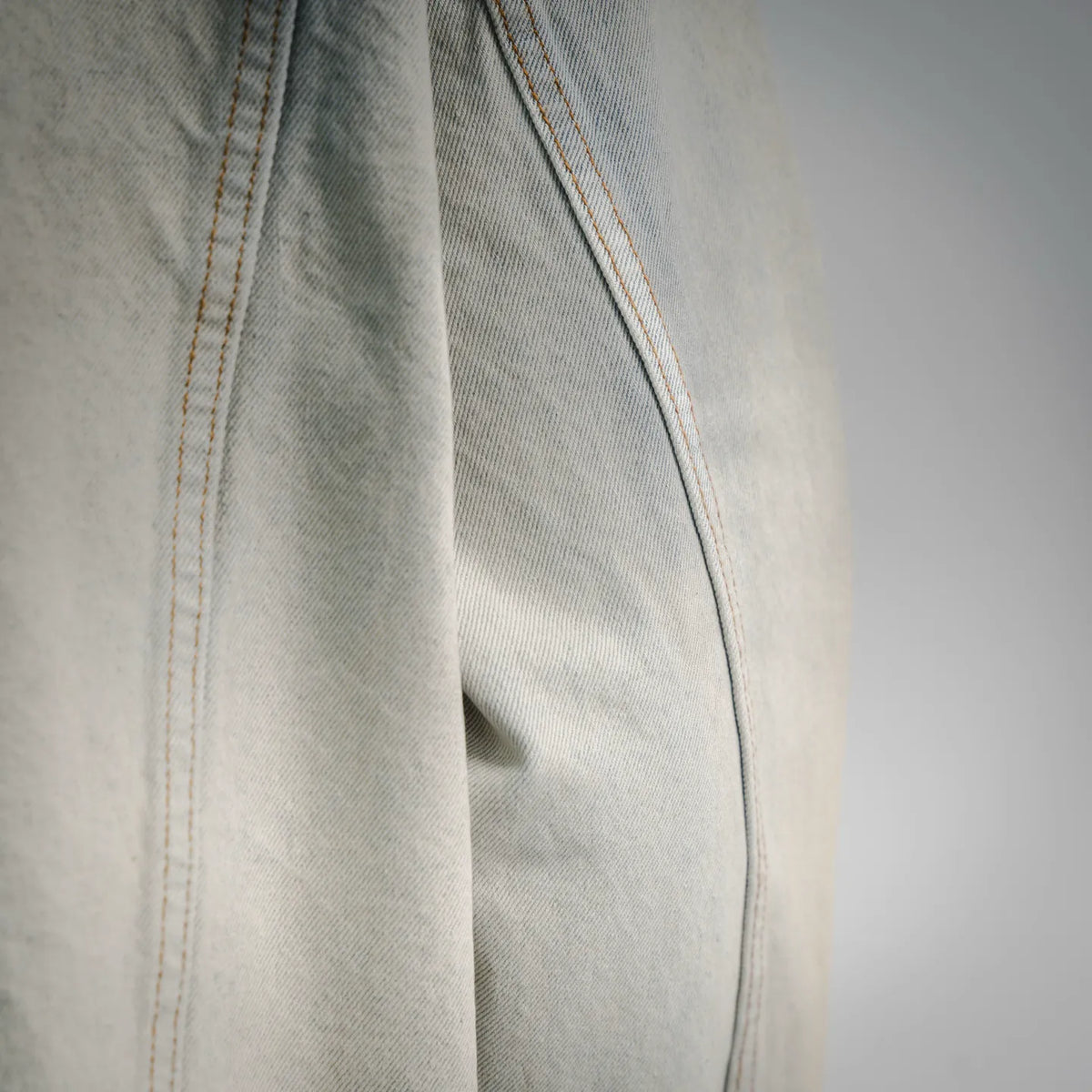 Light-wash denim sleeve with contrast orange stitch detail