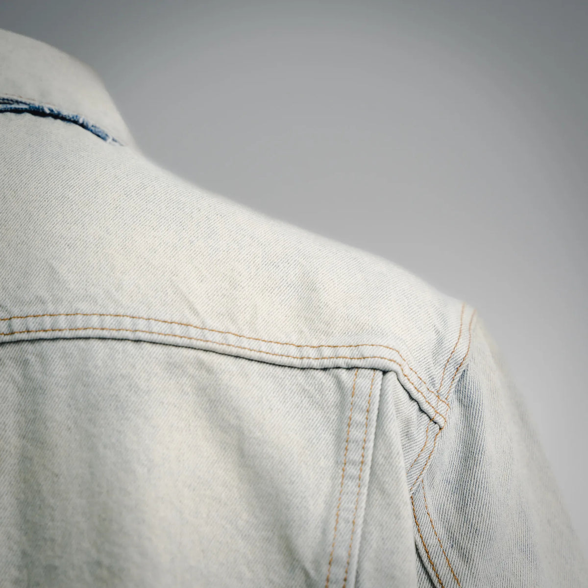 Light-wash denim coat shoulder yoke with topstitching and seam panel