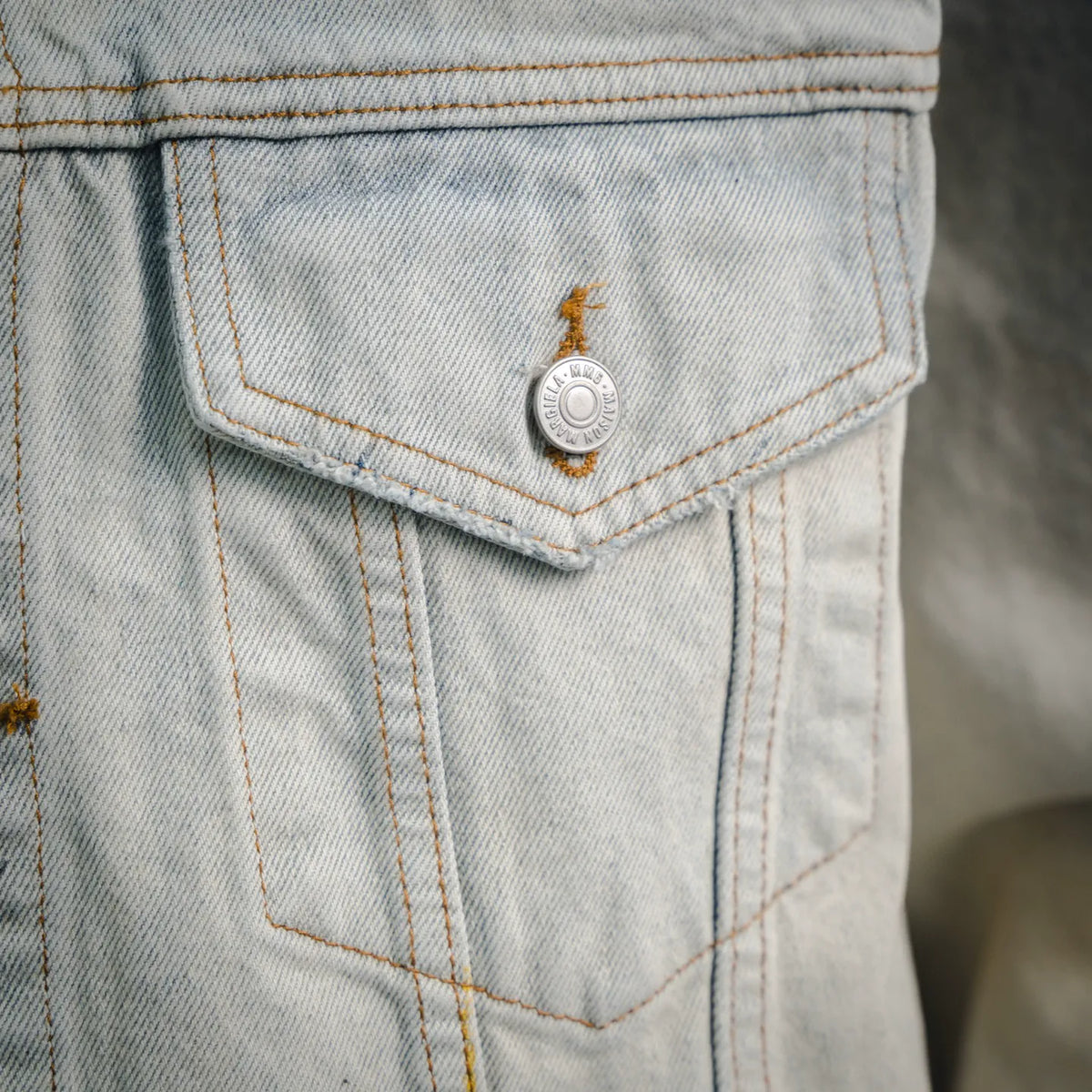Light-wash denim chest pocket with button and contrast orange topstitching