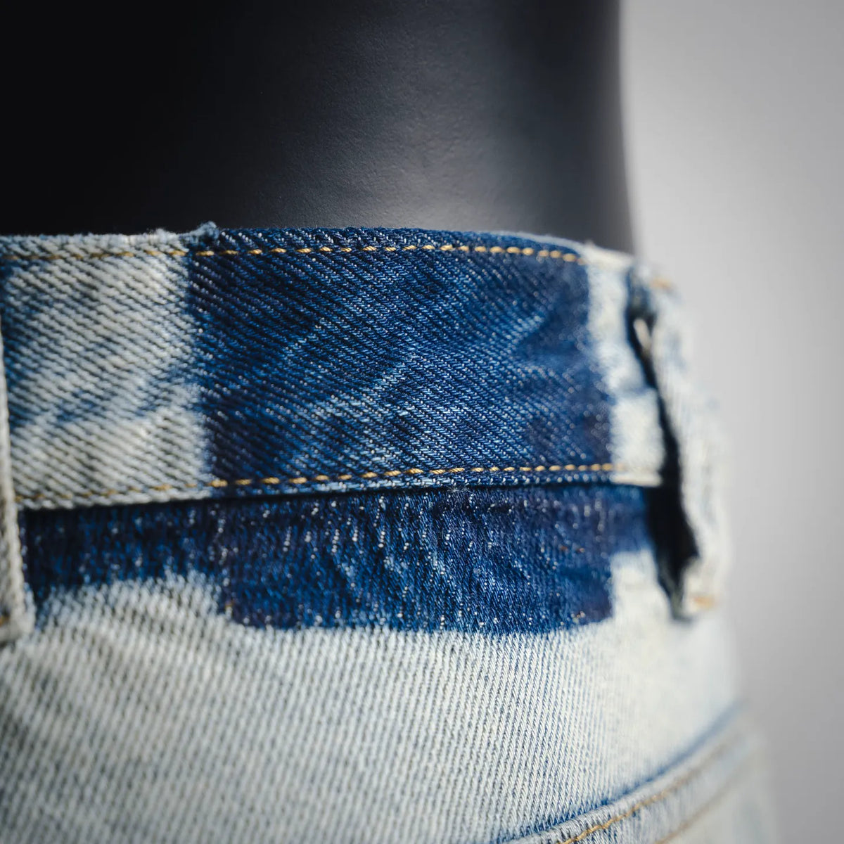 Denim waistband close-up with blue topstitching and worn wash texture