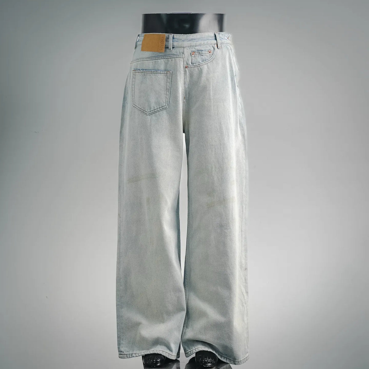 Light-wash denim pants with orange-stitched waistband and relaxed wide-leg fit