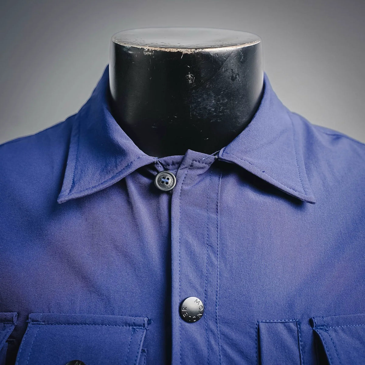 Blue button-up jacket collar with round logo snap buttons on placket