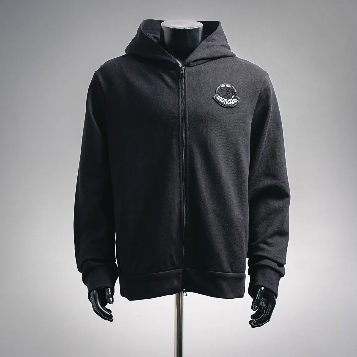 Black zip-up hoodie jacket with Moncler chest logo patch.