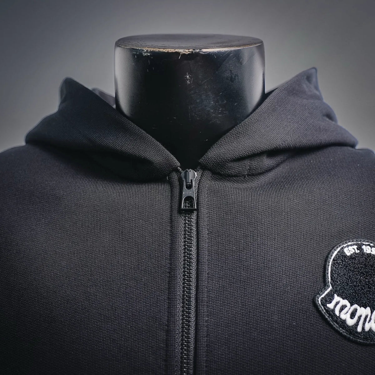 Black zip-up hoodie with hood and front Moncler logo patch.