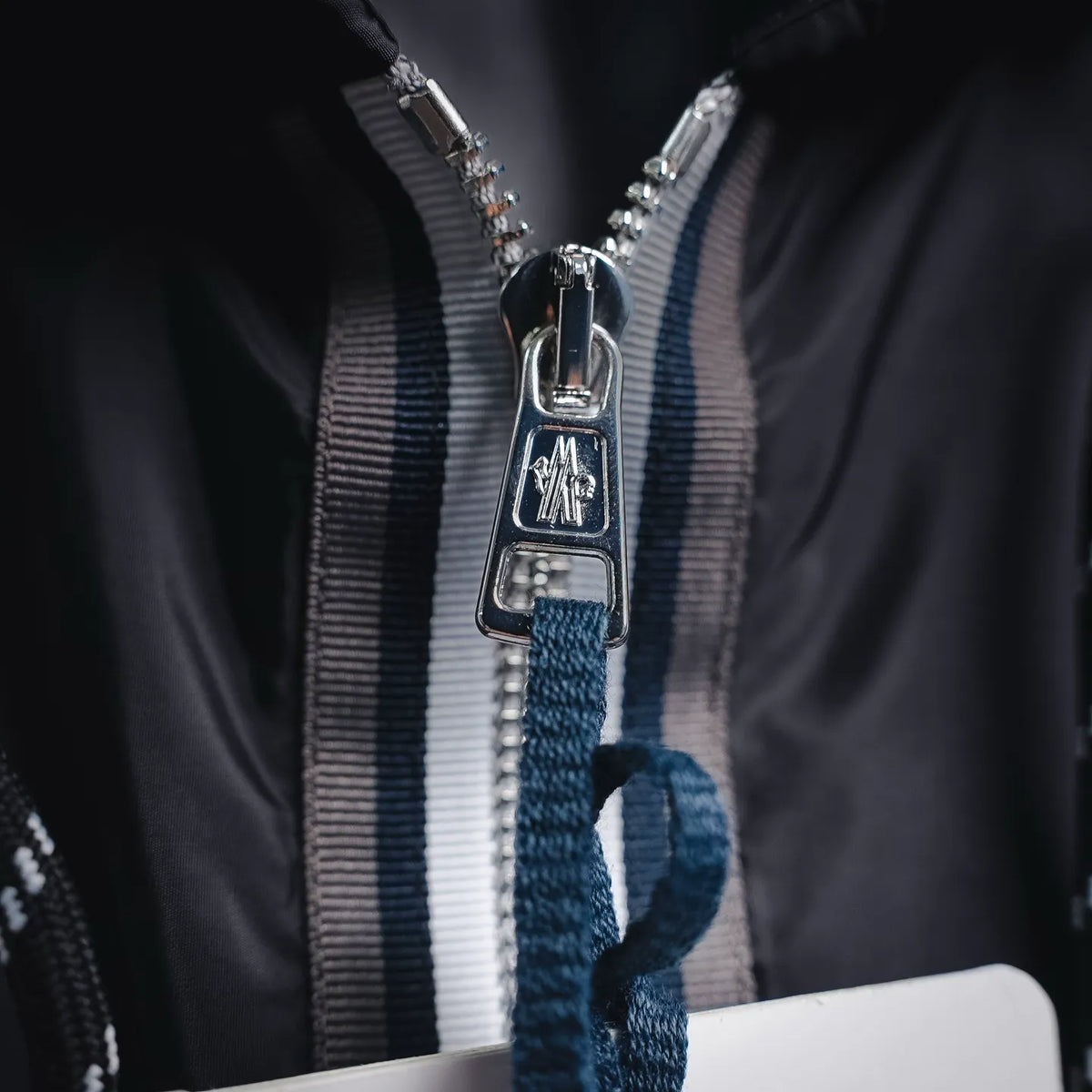 Moncler coat zipper pull and striped inner placket with hanging fabric