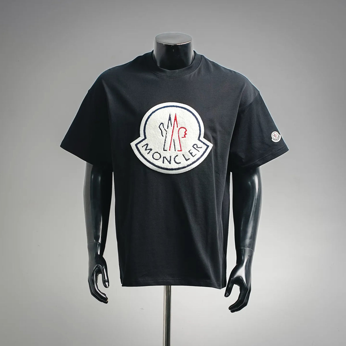 Black short-sleeve T-shirt with Moncler logo patch at chest.