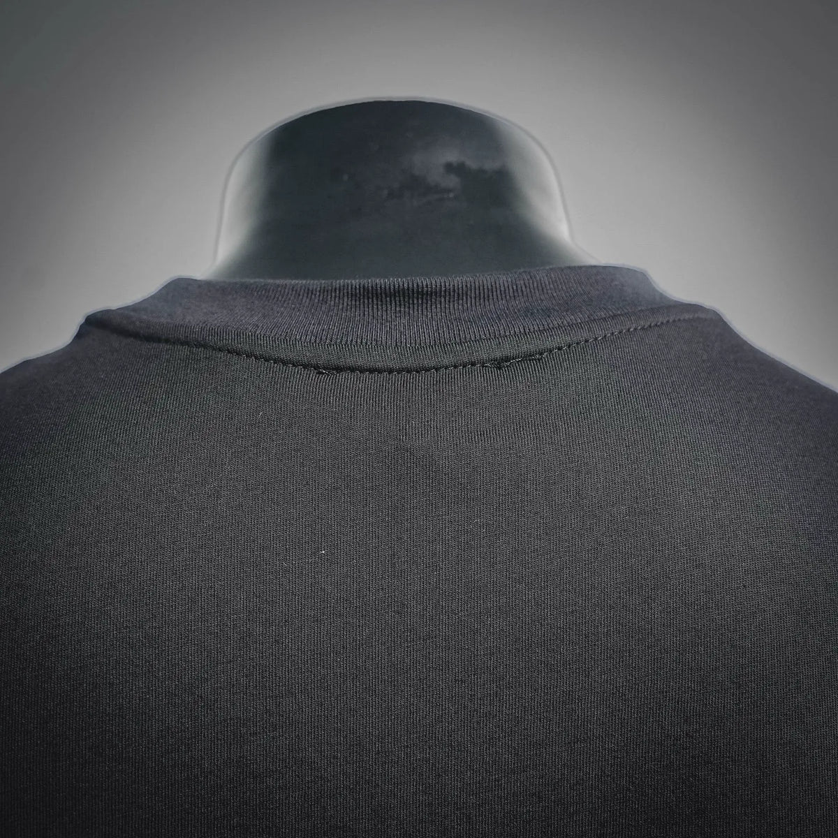 Men's crewneck T-shirt collar ribbed trim on dark fabric, back close-up