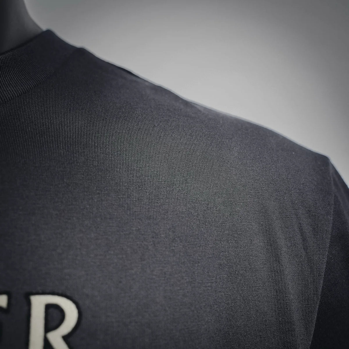 Men's dark crewneck T-shirt, close-up of shoulder seam and knit texture
