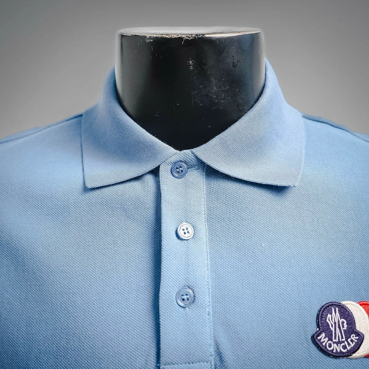 Light blue polo shirt front with three-button placket and Moncler logo patch