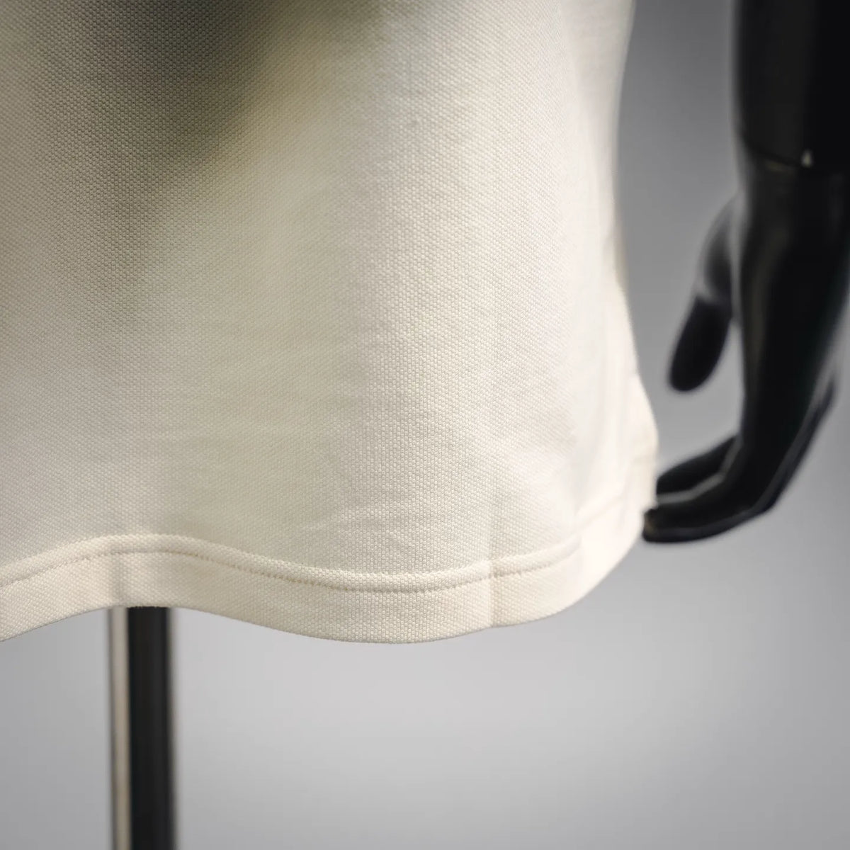 Moncler polo shirt hem close-up, light cream knit with stitched edge