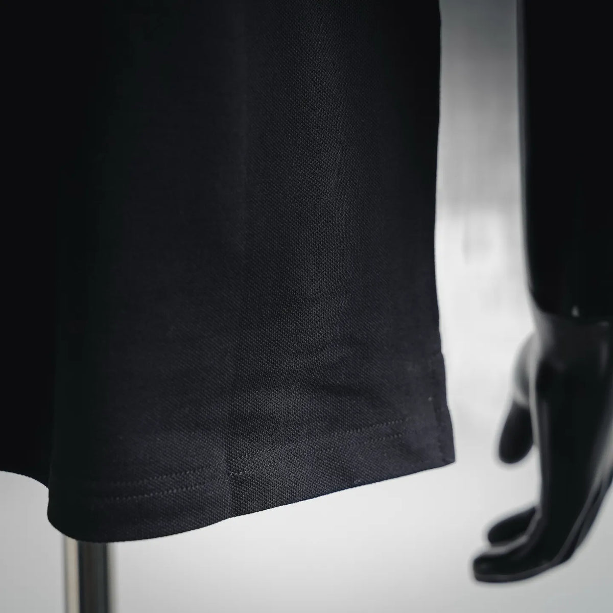 Black polo shirt lower hem with textured knit and side seam