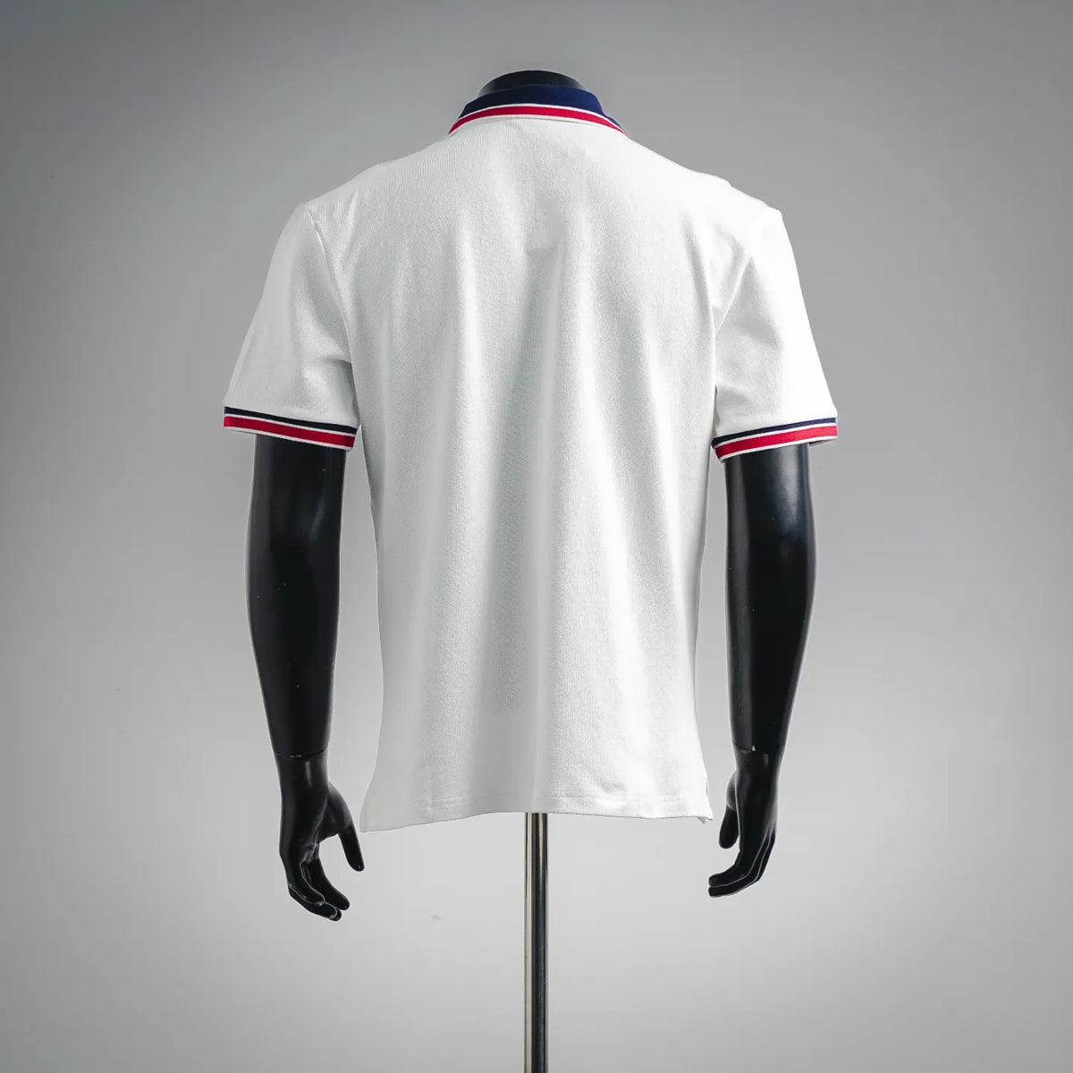 White polo shirt back view with navy collar and red/white striped sleeve hems