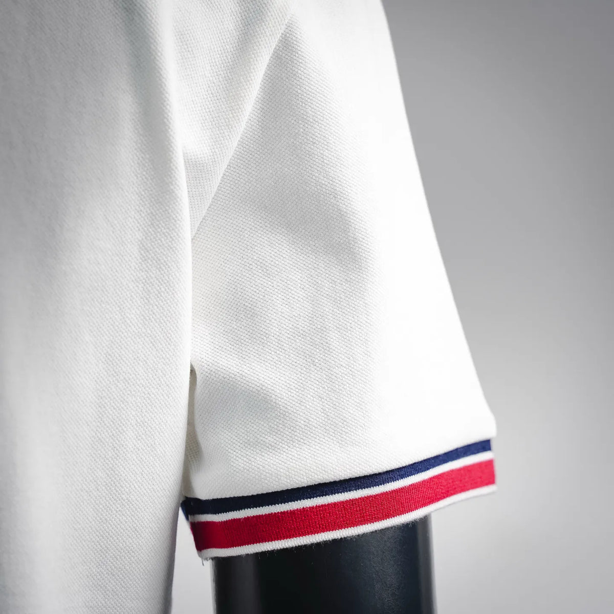 White polo shirt sleeve cuff with navy and red striped trim