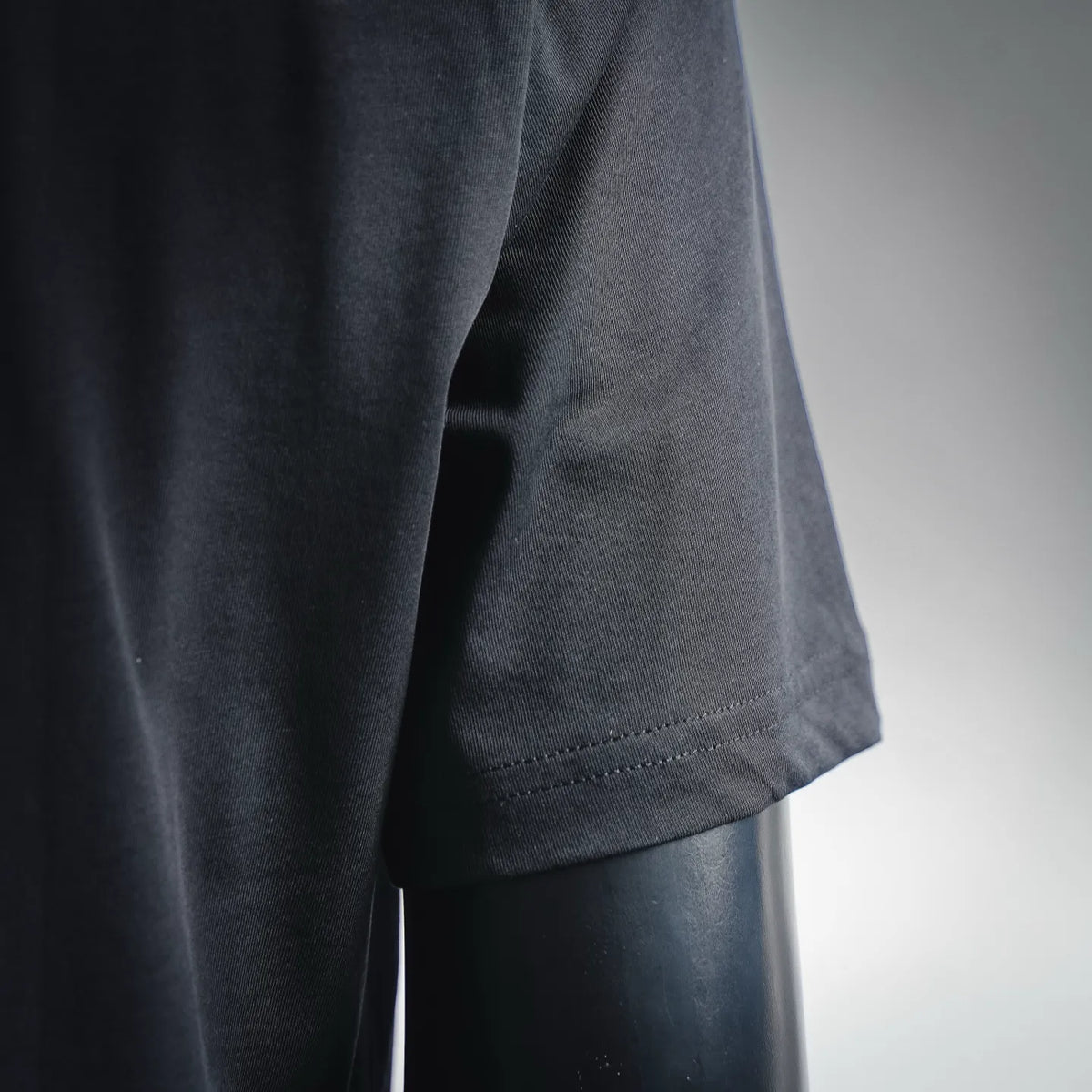 Dark short-sleeve T-shirt fabric close-up with stitched sleeve hem