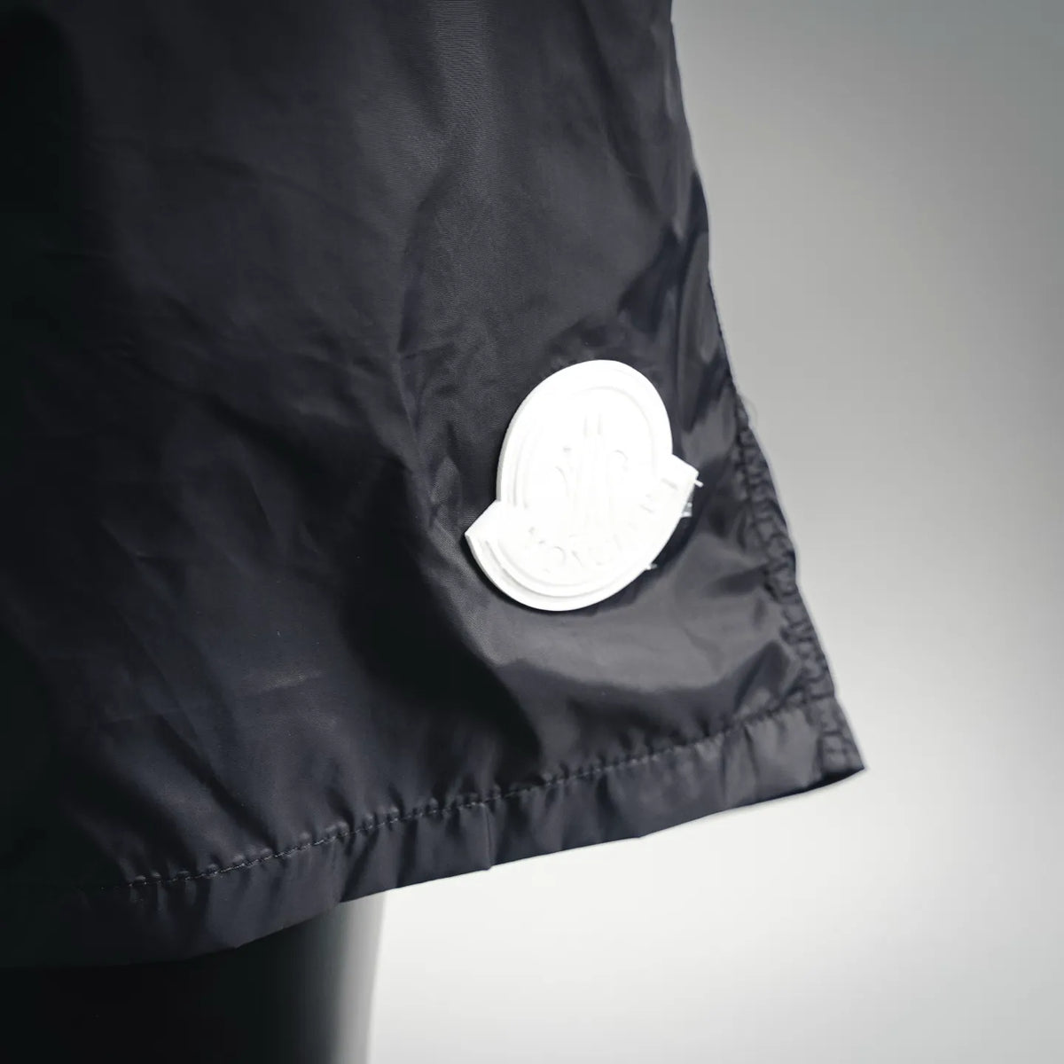 Moncler black swim shorts with round white logo patch near hem