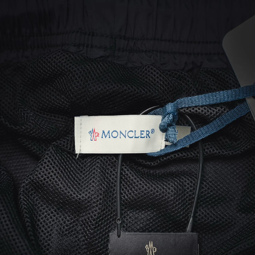 Moncler black swim shorts with brand label, drawstrings, and hang tag