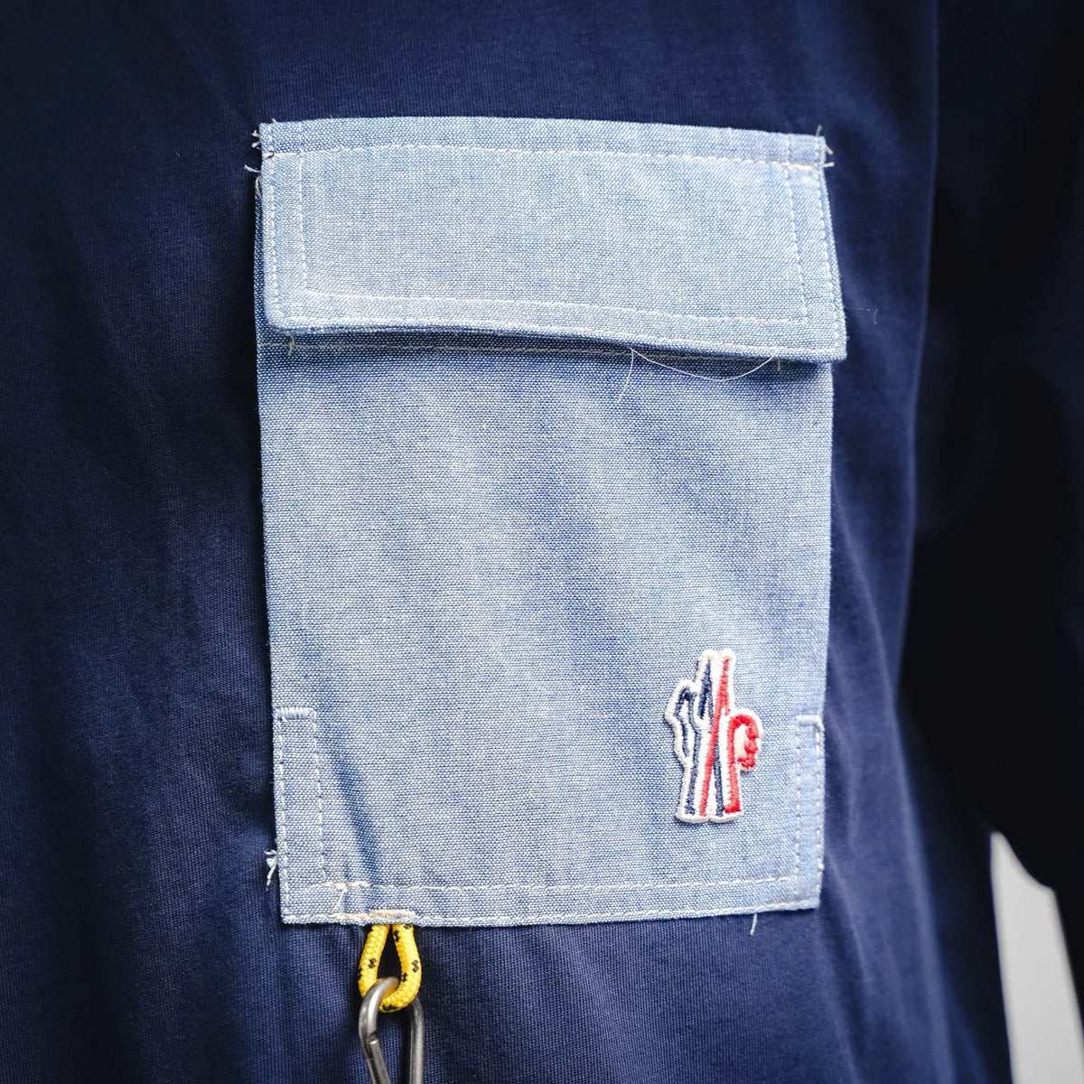 Navy T-shirt with light-gray patch pocket, zipper pull, and small logo embroidery