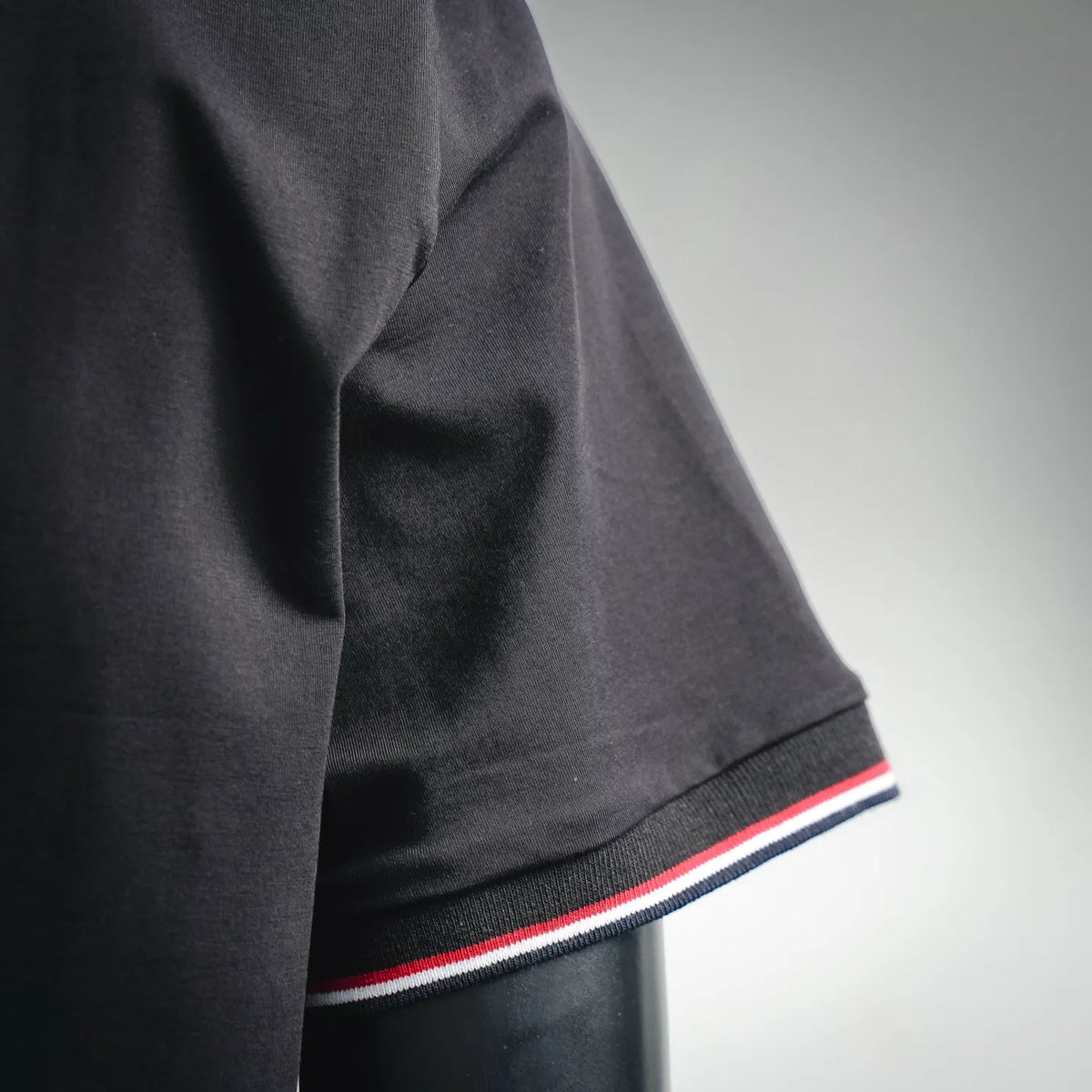 Black T-shirt sleeve with red, white, and blue striped cuff trim