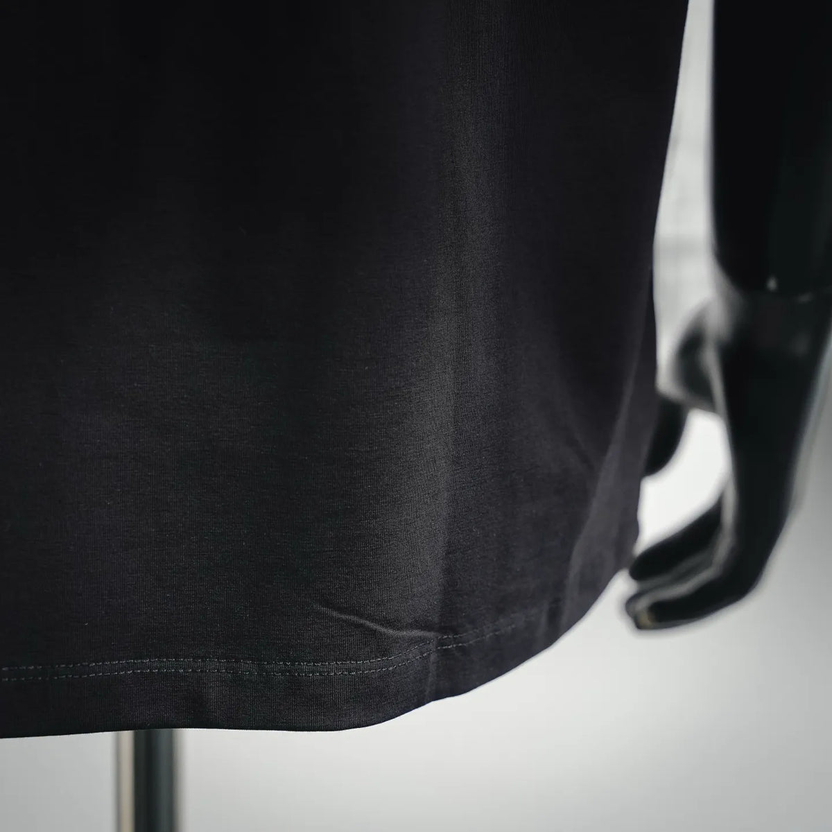 Black T-shirt hem with stitching detail and curved side shape