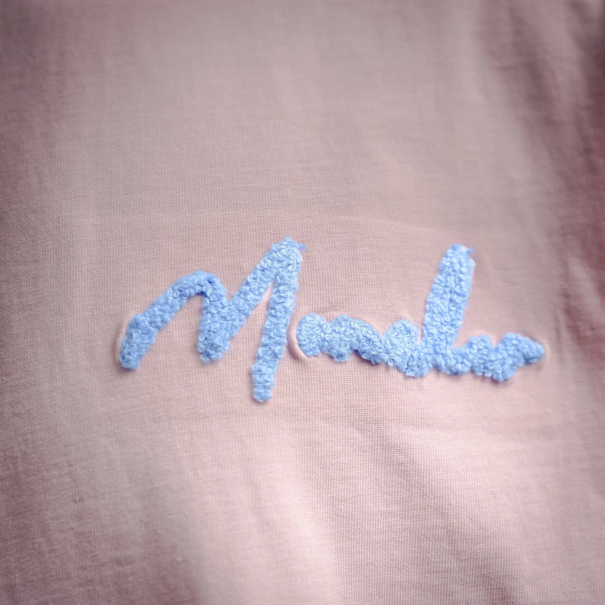 Pink T-shirt front with raised blue cursive “Moncler” embroidered logo