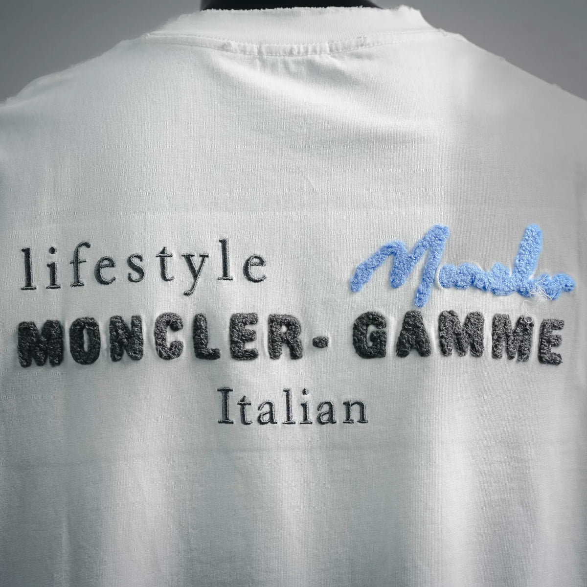 White Moncler T-shirt back logo text with blue cursive 'Moncler'