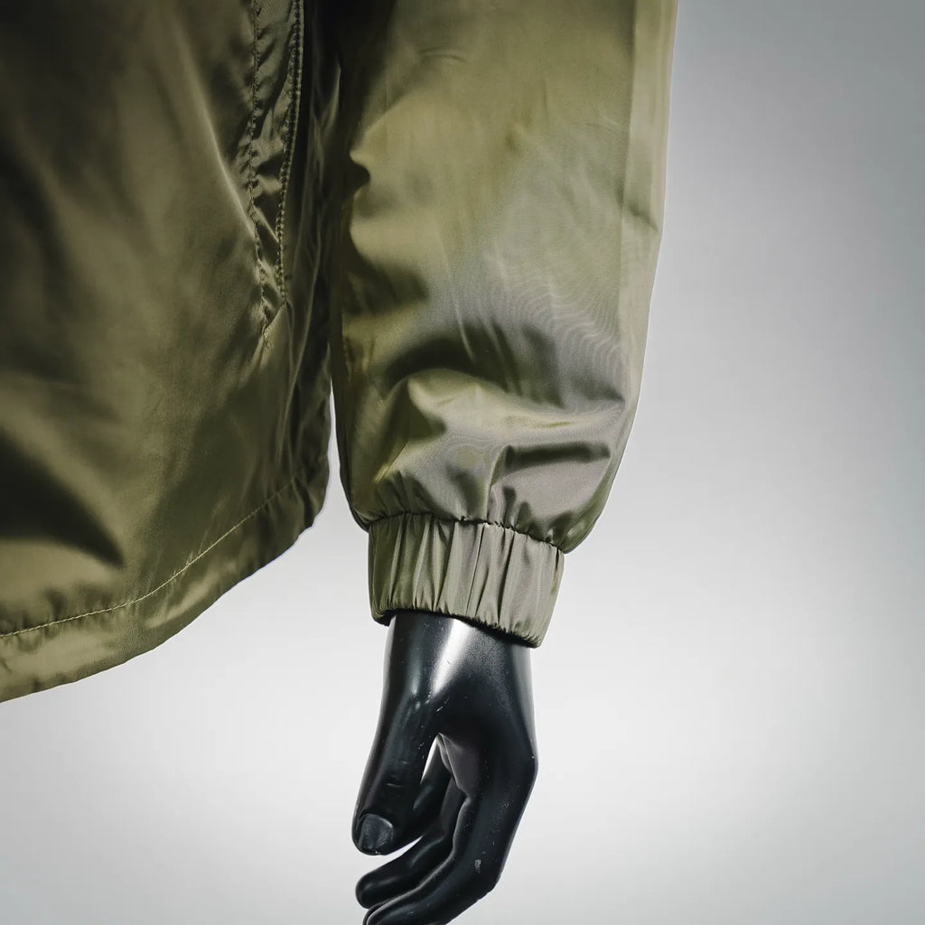 Olive green jacket sleeve cuff with elastic band, close-up on arm and hand