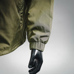 Olive green jacket sleeve cuff with elastic band, close-up on arm and hand