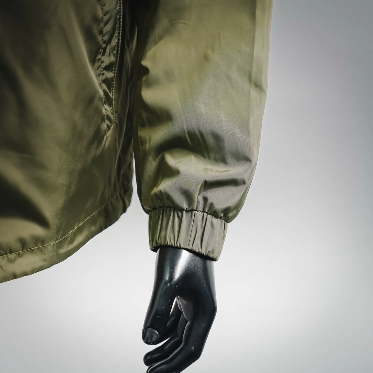 Olive green jacket sleeve cuff with elastic band, close-up on arm and hand