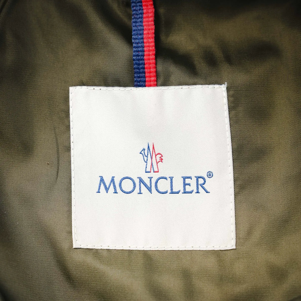 Moncler fabric label on olive green jacket with red and blue stripe trim