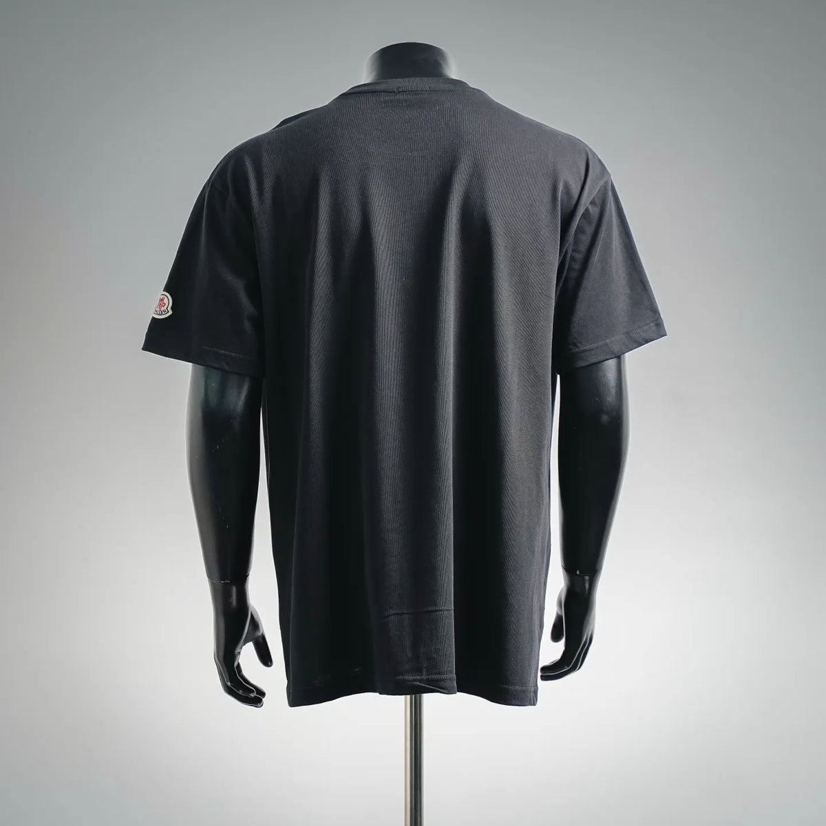 Black crew-neck T-shirt with small sleeve logo patch on the left side