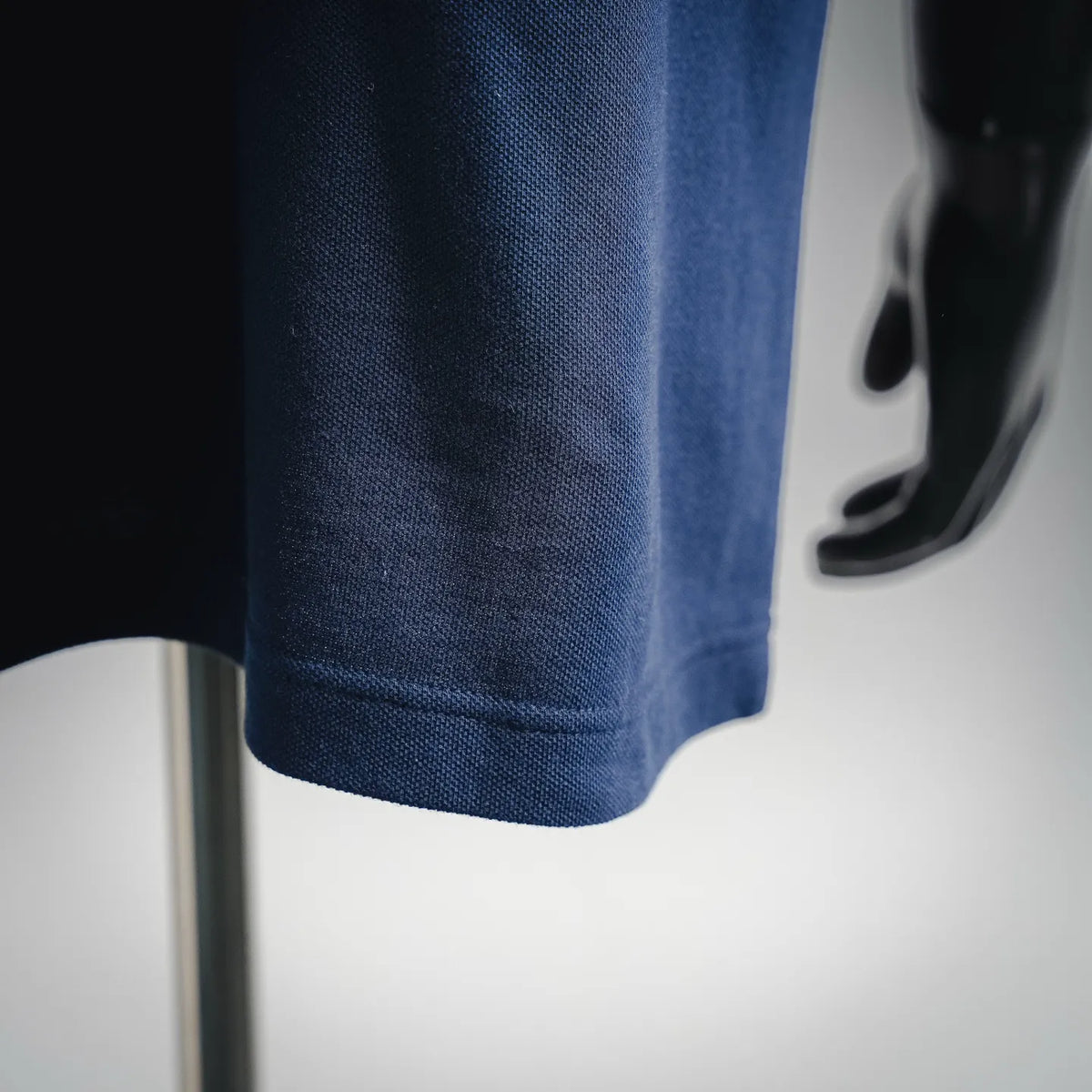 Dark blue polo fabric texture close-up with short-sleeve hem