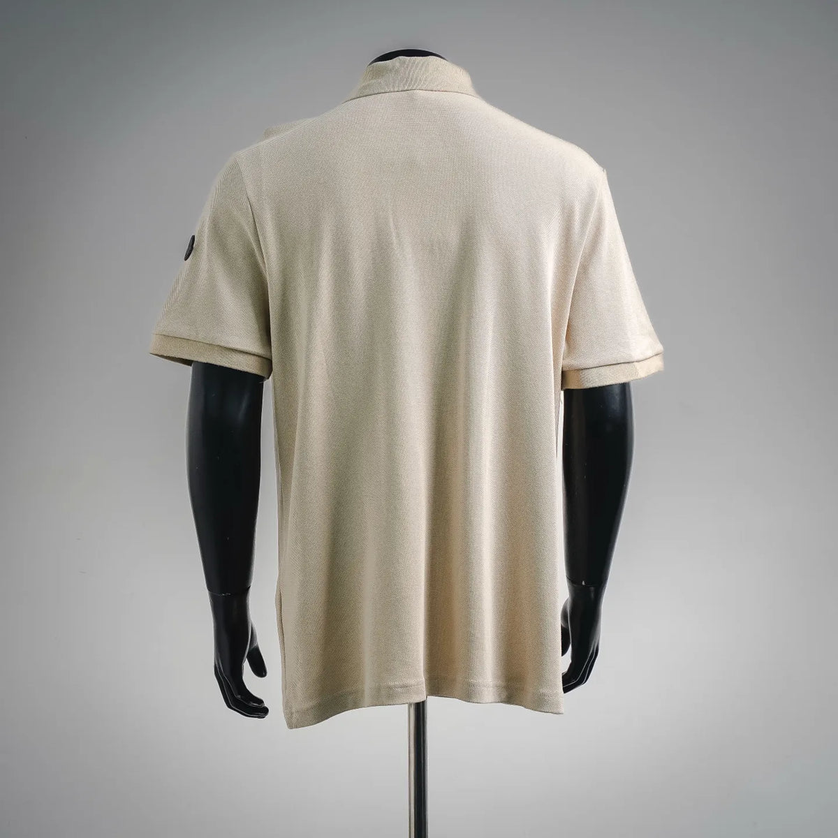 Moncler short-sleeve polo shirt, light beige, shown from the back on a mannequin.