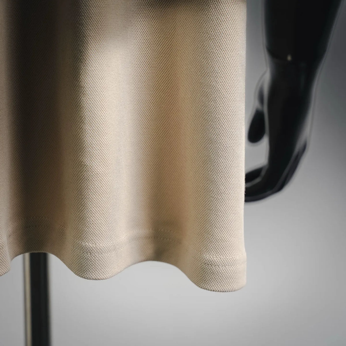 Moncler light beige polo shirt hem with ribbed trim and fine textured fabric close-up.