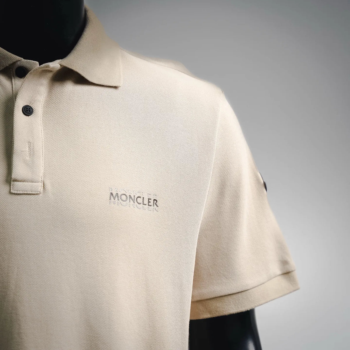 Moncler light beige polo shirt with collar, button placket, and small chest logo.