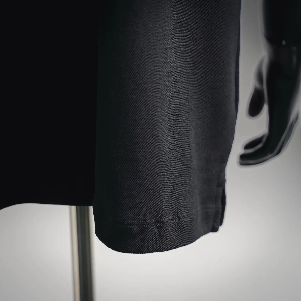 Black textured polo fabric close-up at the hem