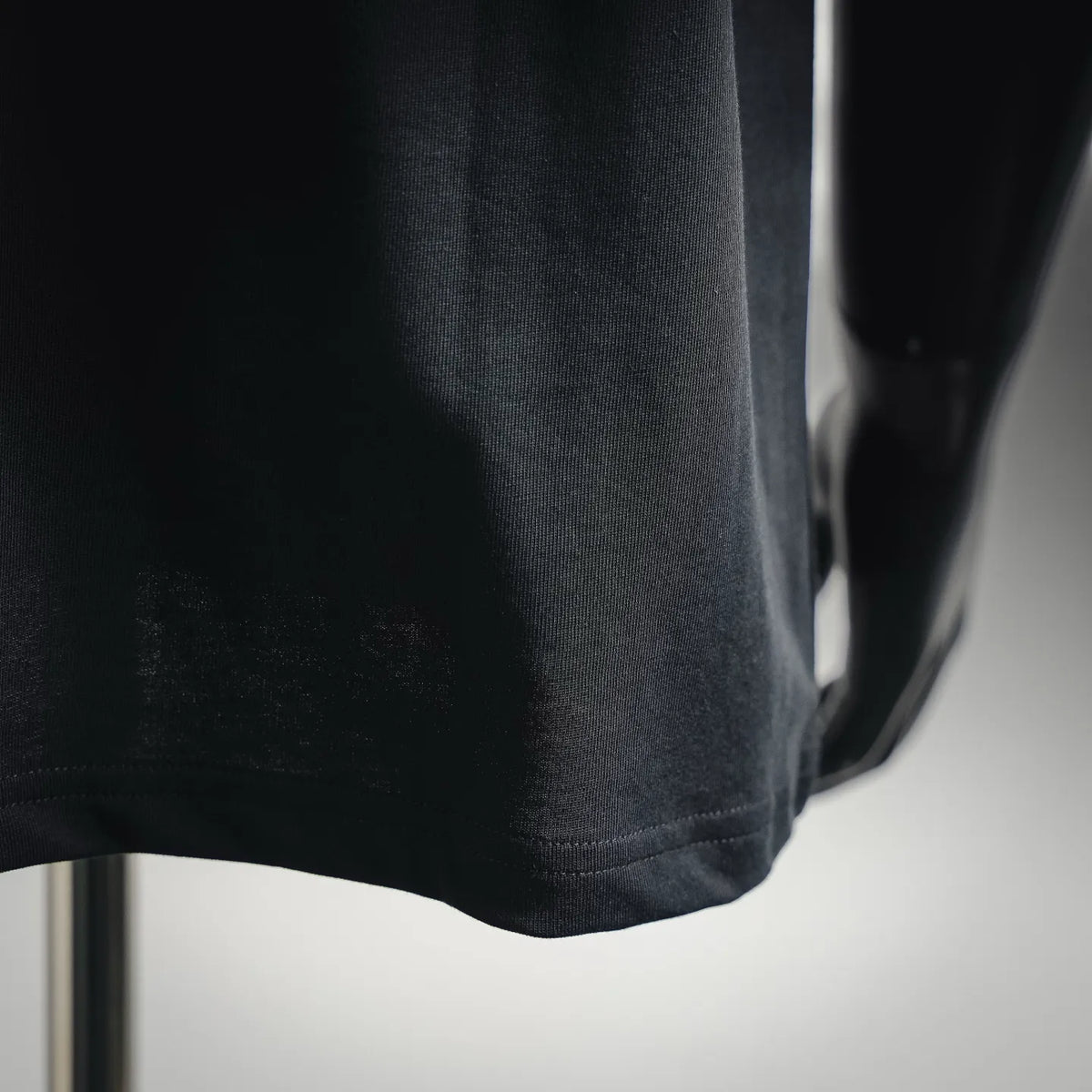 Moncler dark T-shirt hem and side seam close-up, short-sleeve bottom edge stitching