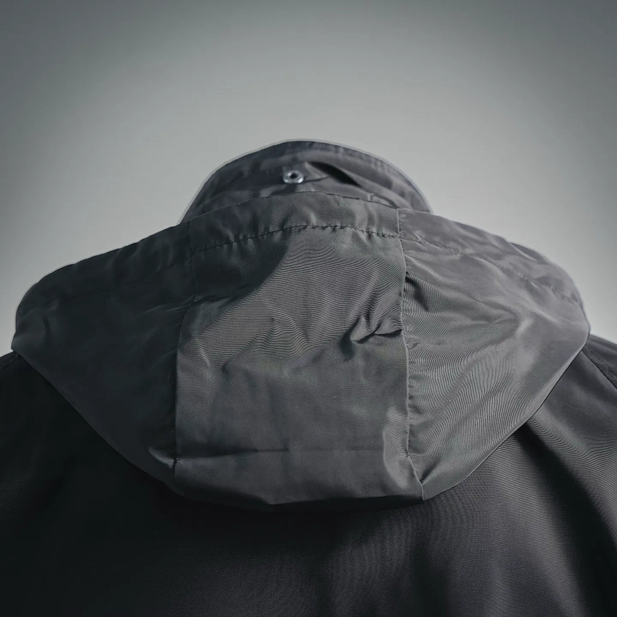 Hooded coat hood with button detail and textured fabric panel.