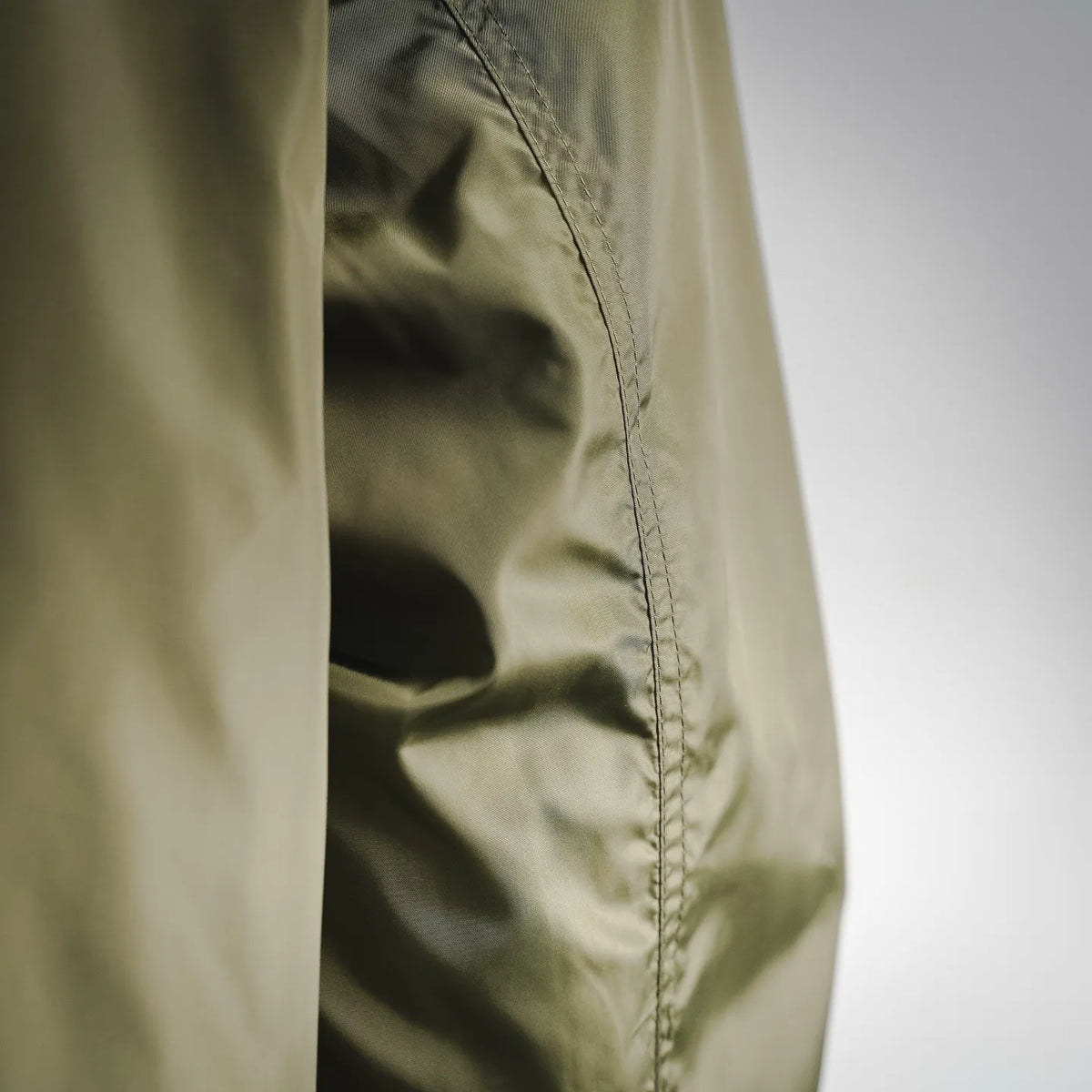 Olive coat side panel with vertical seam and button placket detail