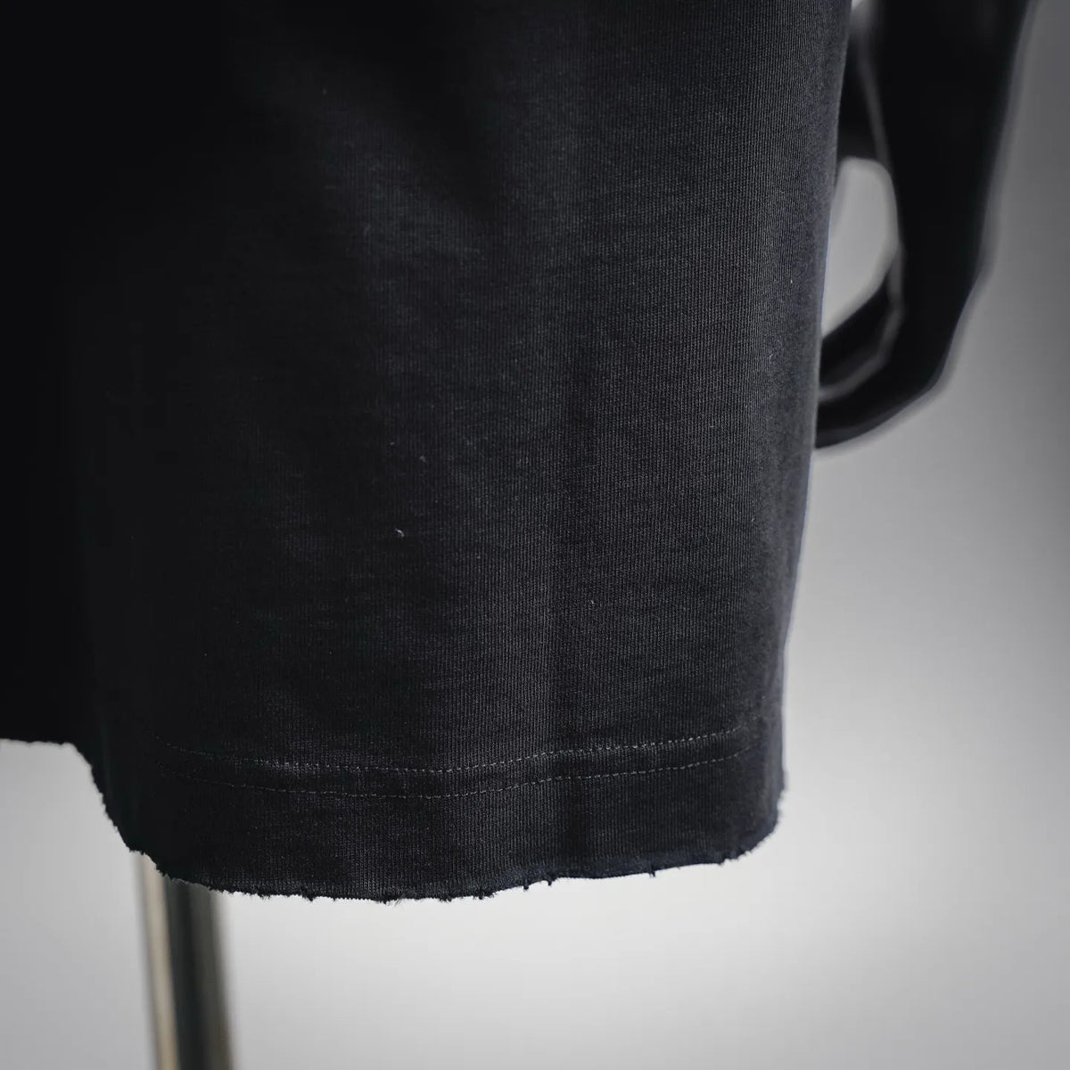 Black short-sleeve T-shirt with stitched curved hem and slightly frayed edge