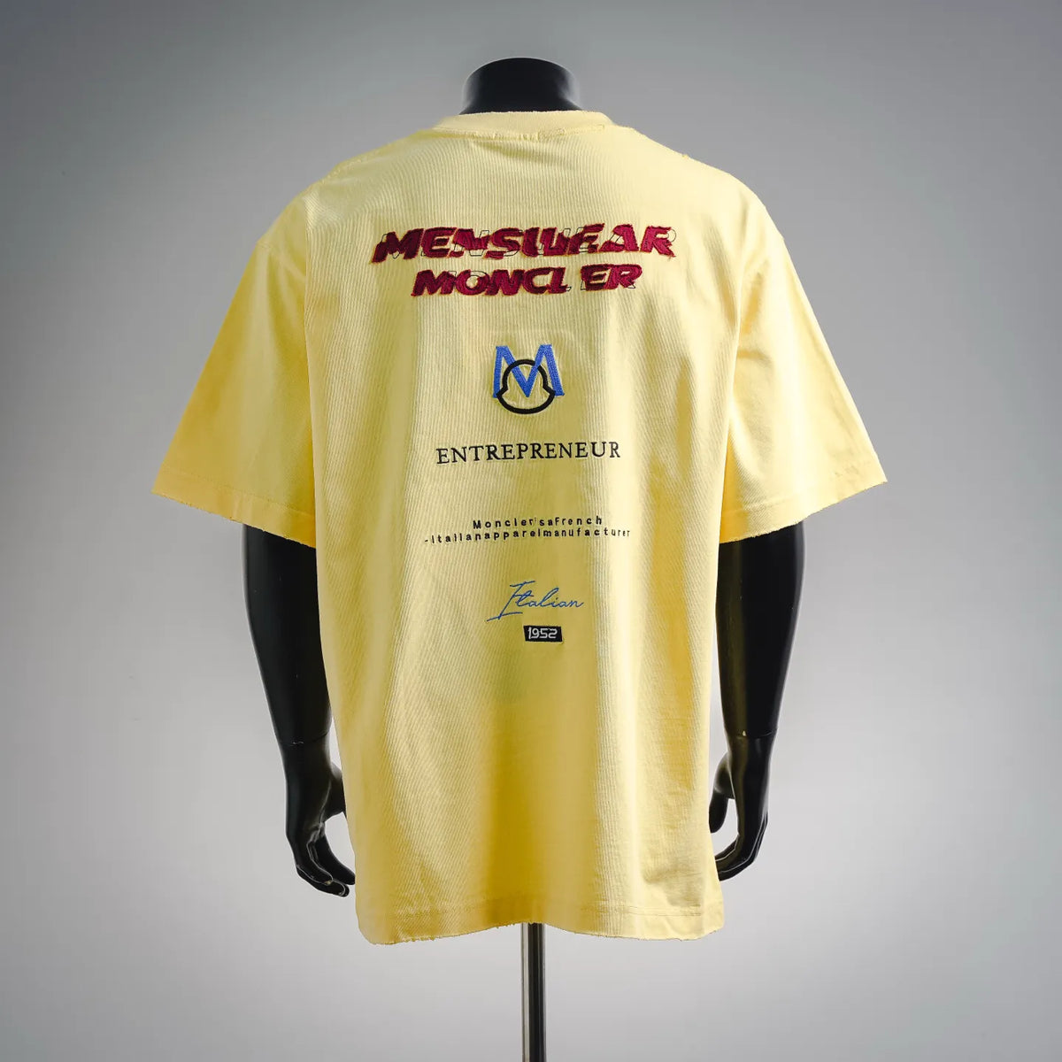 Men's yellow short-sleeve t-shirt, back graphic with red text and blue M emblem