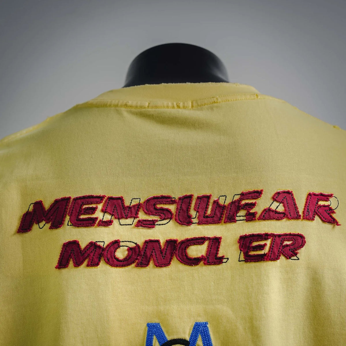 Men's yellow t-shirt back panel with large red “MONCLER” lettering graphic